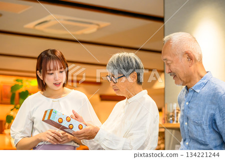 A young woman gives a souvenir to an elderly couple 134221244