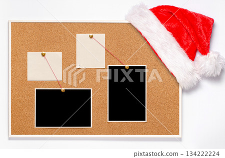 Blank paper notes and an empty photo are pinned to a cork board. Santa's hat on a cork board 134222224