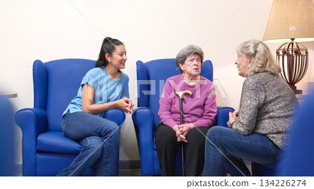 Family visiting elderly women in nursing home lounge Family visiting elderly women in nursing home lounge 134226274