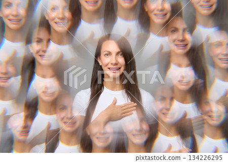 Creative optical illusion portrait of woman with multiple reflections holding hand on chest smiling 134226295