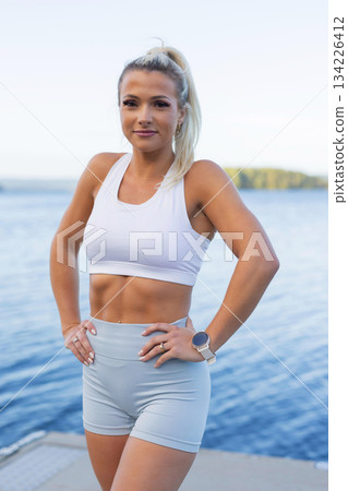 Fit woman outdoors by the water wearing activewear and monitoring fitness progress 134226412