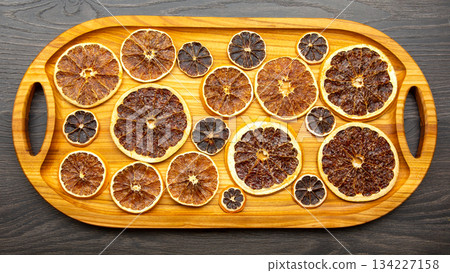 dried citrus fruit pieces are laid out on a wooden board for product transfer. vitamin food 134227158