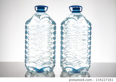 Two large plastic water bottles with blue caps  134227161