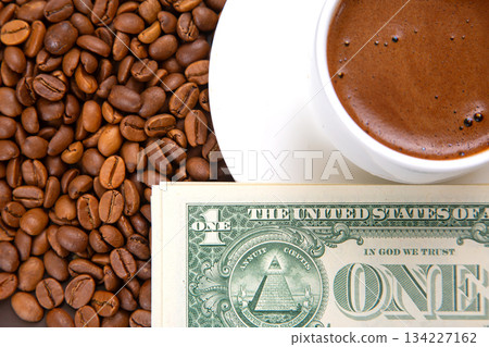 Freshly brewed coffee in a white cup on a saucer, next to a heap of roasted beans Freshly brewed coffee in a white cup on a saucer, next to a heap of roasted beans 134227162