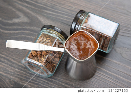 Close-up of a silver cezve with frothy Turkish coffee on a wooden table, 134227163