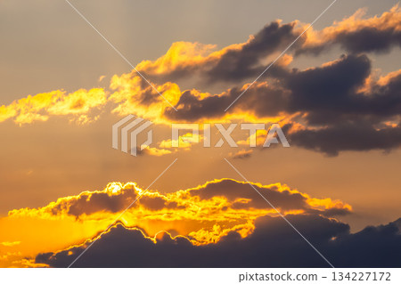 Ethereal sky filled with heavy clouds and golden light rays breaking through at sunset Ethereal sky filled with heavy clouds and golden light rays breaking through at sunset 134227172