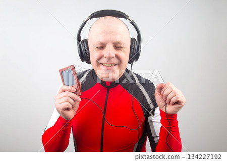 happy man in portable full-size headphones listens to music using a digital player. 134227192