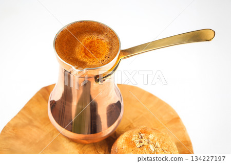 traditional clay cezve filled with frothy Turkish coffee on a warm wooden table traditional clay cezve filled with frothy Turkish coffee on a warm wooden table 134227197