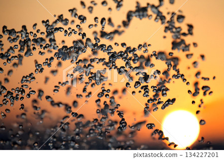 silhouettes of drops falling water fountain against the backdrop of the setting sun silhouettes of drops falling water fountain against the backdrop of the setting sun 134227201