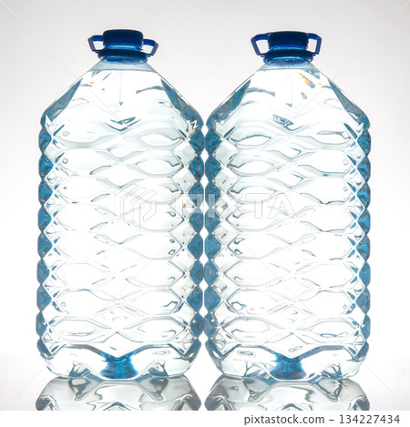 A pair of clear plastic water bottles with blue lids, featuring a wavy texture 134227434