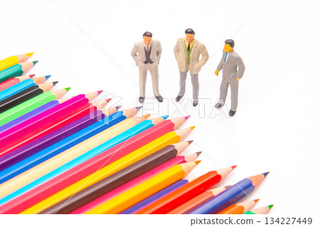Brightly colored pencils fanned out on white backdrop, paired with three miniature business figures Brightly colored pencils fanned out on white backdrop, paired with three miniature business figures 134227449