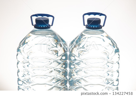 A pair of clear plastic water bottles with blue lids, featuring a wavy texture 134227458