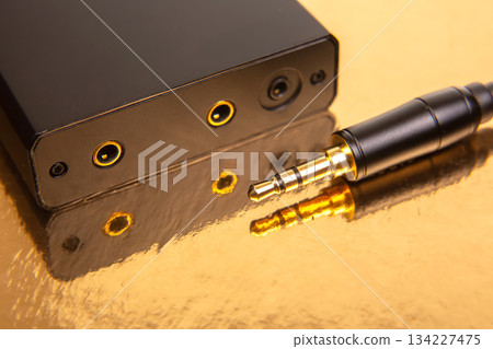 Detailed view of 3.5mm audio plugs with gold connectors on a glossy golden surface 134227475