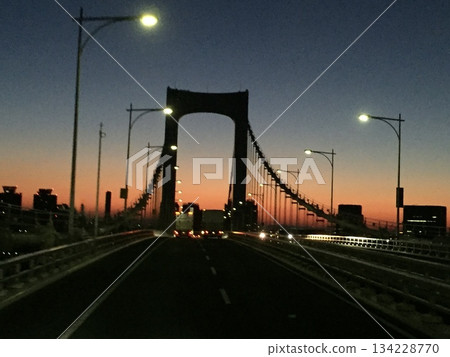 A view of a bridge and road under a sunset sky 134228770