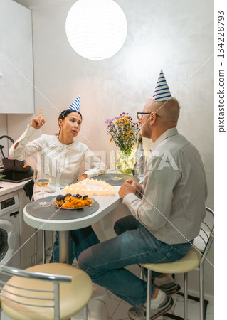 Birthday Couple Kitchen Celebration: Happy couple celebrates birthday with cake in apartment kitchen; intimate setting. Birthday Couple Kitchen Celebration: Happy couple celebrates birthday with cake in apartment kitchen; intimate setting. 134228793