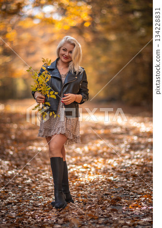 Woman Autumn Fashion Photography: Blonde model poses leaves forest path October photoshoot. 134228831