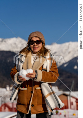 Snowball Mountains Winter: Woman playfully holds snowball, enjoying sunny winter day in mountainous region. Snowball Mountains Winter: Woman playfully holds snowball, enjoying sunny winter day in mountainous region. 134228901