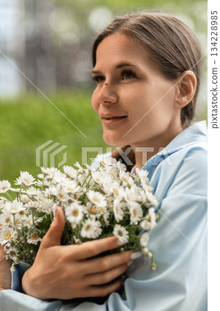 Daisies Woman Portrait: Brunette holds flowers outdoor, smiling in daylight for happiness. Daisies Woman Portrait: Brunette holds flowers outdoor, smiling in daylight for happiness. 134228985
