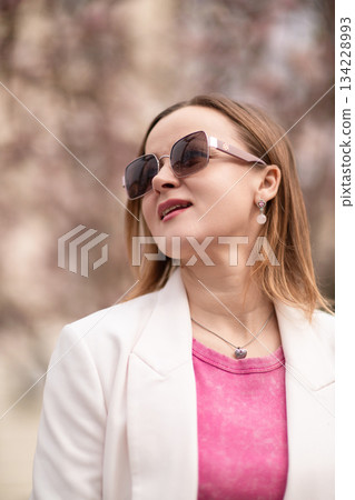 Woman Sunglasses Springtime: Woman enjoys sunny day in park during spring, wearing sunglasses, light jacket. 134228993