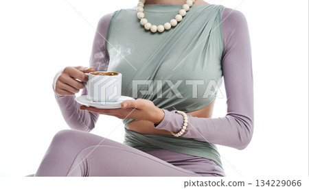 Woman holds a steaming cup in a modern setting with a focus on fashion and lifestyle 134229066