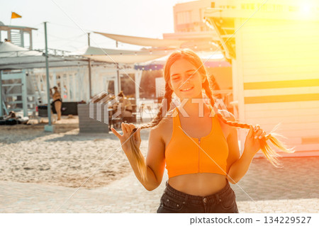 Woman Beach Summer: Happy girl braids hair near beach cabins, sunny day. 134229527