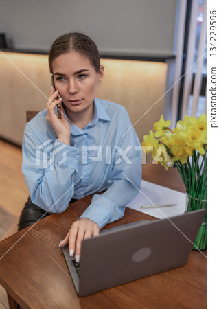 Businesswoman phone working attentive professional talking discussing communication laptop office Businesswoman phone working attentive professional talking discussing communication laptop office 134229596
