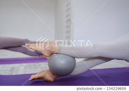 Pilates ball stability exercise legs using fitness equipment in a bright gym 134229609