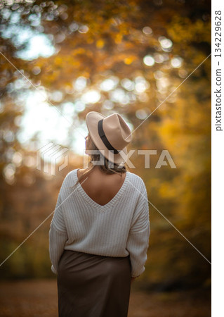 Woman Autumn Forest Hat: Back view, Fall fashion, outdoor portrait, nature scenery. Woman Autumn Forest Hat: Back view, Fall fashion, outdoor portrait, nature scenery. 134229628