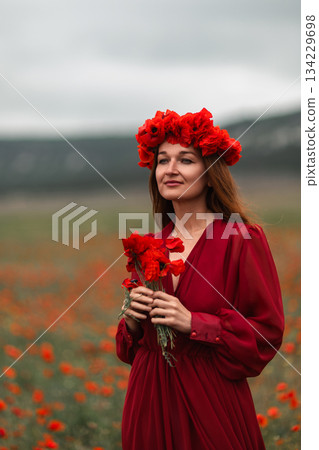 Woman poppies field emotional portrait in blooming meadow with moody cloudy sky Woman poppies field emotional portrait in blooming meadow with moody cloudy sky 134229698