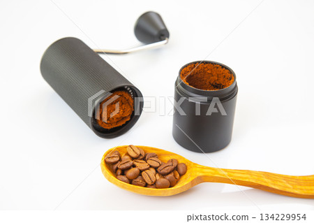 manual coffee grinder, opened to show ground coffee, with some powder spilled on a white background manual coffee grinder, opened to show ground coffee, with some powder spilled on a white background 134229954