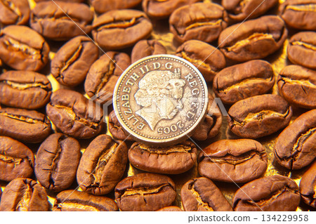Roasted coffee beans with a dime for scale on a golden backdrop 134229958