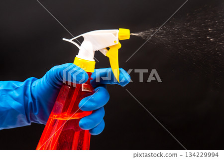 blue-gloved hand using a red spray bottle  134229994