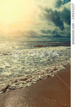 Sunset over the sea. Waves roll onto the sandy shore. Nature abstract background. Vertical banner Sunset over the sea. Waves roll onto the sandy shore. Nature abstract background. Vertical banner 134231217