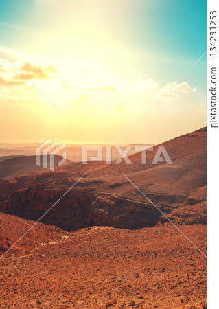 Mountainous desert with colorful cloudy sky. Judean desert in Israel at sunset. Vertical banner 134231253