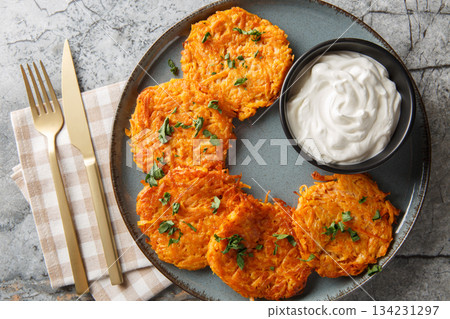 Vegetarian fritters from sweet potato served with sour cream closeup on the plate. Horizontal top view 134231297