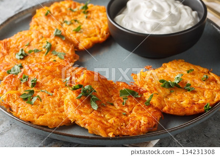 Sweet Potato Hash Browns with crispy edges and a buttery center served with sour cream closeup on the plate. Horizontal Sweet Potato Hash Browns with crispy edges and a buttery center served with sour cream closeup on the plate. Horizontal 134231308