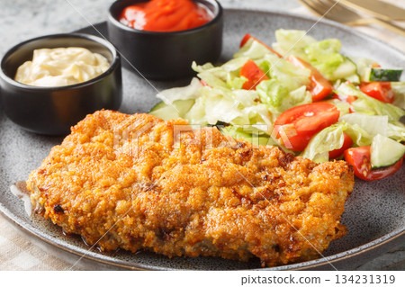 Breaded Sicilian Steak or Bistecca Alla Siciliana with salad and sauces closeup on the plate. Horizontal Breaded Sicilian Steak or Bistecca Alla Siciliana with salad and sauces closeup on the plate. Horizontal 134231319