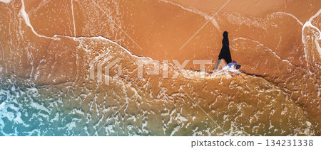 Seascape from above. A woman walks on the beach in summer. Travel happy holiday and summertime concept. Top view. Horizontal banner 134231338