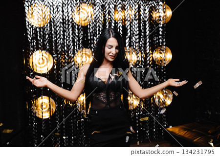 Beautiful happy woman at celebration party with confetti falling everywhere on her. Birthday or New Year eve celebrating concept Beautiful happy woman at celebration party with confetti falling everywhere on her. Birthday or New Year eve celebrating concept 134231795