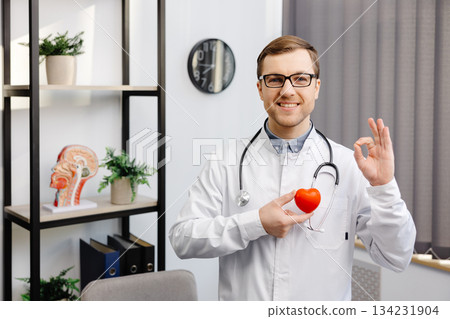 Doctor in white coat and glasses holding a red heart at hospital office. Medical health care and doctor staff service concept 134231904