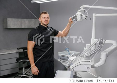 Male dentist adjusting dental light in modern clinic 134232133