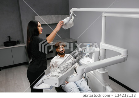 Dental assistant preparing lamp for patient checkup 134232138