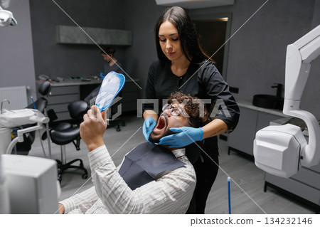 Dentist examining patient mouth during dental check-up 134232146