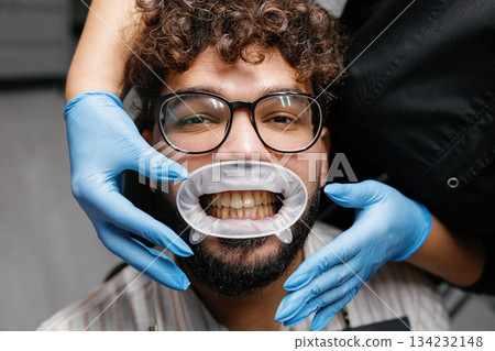 Patient receiving dental checkup with mouth expander 134232148