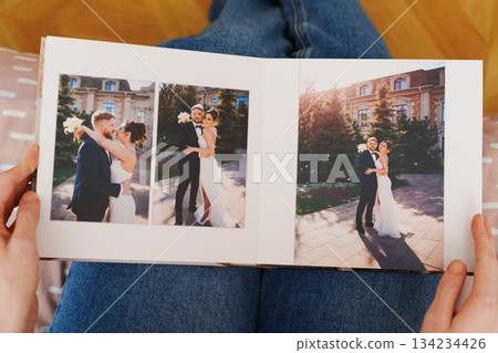 Female hands flipping through a photo book with wedding photos 134234426