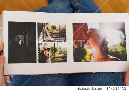 Female hands flipping through a photo book with wedding photos 134234430