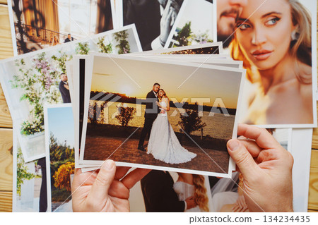 Men's hands put on the table and show wedding photos. Men's hands put on the table and show wedding photos. 134234435