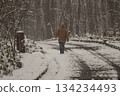 Back view of a person walking on a snowy road 134234493