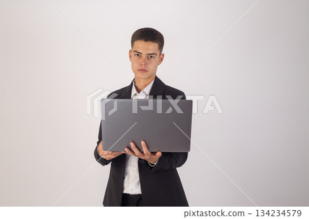 Young man walking with a laptop, dressed in a business casual style 134234579