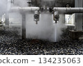 Steam is coming out of a pipe and the ground is covered in rocks 134235063